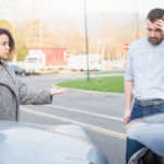 Man and woman arguing after bad car crash