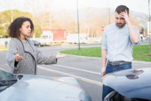 Man and woman arguing after bad car crash