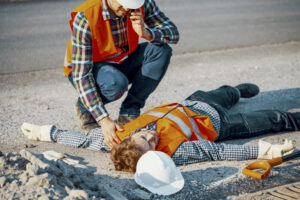 Worried man calling ambulance for his unconscious coworker