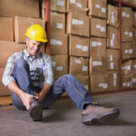Worker with sprained ankle on floor in warehouse Worker with sprained ankle on floor in warehouse