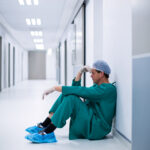 ensed male surgeon sitting in corridor