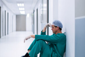ensed male surgeon sitting in corridor