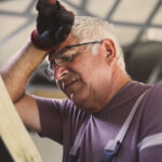 Senior man in workshop. Worried man reading his planner.