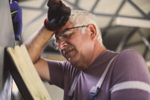 Senior man in workshop. Worried man reading his planner.